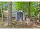 Backyard shed with double doors and wood storage, nestled among mature trees at 907 Lingfield Ln, Waxhaw, NC 28173