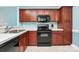 Functional kitchen with wood cabinets and black appliances and tile floors at 9212 Scotts Elm Ct, Charlotte, NC 28215