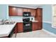 Functional kitchen with wood cabinets and black appliances and tile floors at 9212 Scotts Elm Ct, Charlotte, NC 28215