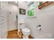 This half bathroom includes a toilet, window, wood floors, and tiled walls with shelving at 1023 Evian Ln, Matthews, NC 28105