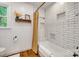This bathroom includes a tub with shower, window, wood floors, and tiled walls with shelving at 1023 Evian Ln, Matthews, NC 28105