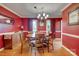 Dining room with red walls, hardwood floors, chandelier, and furniture at 1023 Evian Ln, Matthews, NC 28105