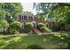 Traditional brick home with a manicured lawn, mature trees and black shutters at 1023 Evian Ln, Matthews, NC 28105
