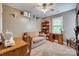 This office features neutral colors, a sofa, a desk, and a bookshelf in front of a window at 1023 Evian Ln, Matthews, NC 28105