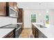 Modern kitchen with stainless appliances, white countertops, and dark cabinets at 106 Kirsche Ct, Mooresville, NC 28115