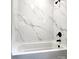 Modern bathtub with stylish marble-patterned tile surround and sleek black fixtures at 11 N 10Th Ave, Maiden, NC 28650