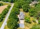 Aerial view of a brick home surrounded by lush trees, a spacious yard, and a long driveway at 1207 Carlson Dr, Monroe, NC 28110