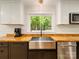 Modern kitchen showcasing a stainless steel sink, butcher block counters, and contemporary fixtures beneath a window at 1207 Carlson Dr, Monroe, NC 28110