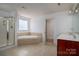 Well-lit bathroom with a shower, soaking tub, vanity, and tile floors, offering comfort and style at 12802 Waterlyn Club Dr, Charlotte, NC 28278