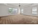 Spacious bedroom with three windows, neutral carpet, and a ceiling fan, offering plenty of light and comfort at 12802 Waterlyn Club Dr, Charlotte, NC 28278