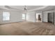 Expansive bedroom featuring a ceiling fan, neutral carpet, and a partial view into a bathroom, providing ample space and comfort at 12802 Waterlyn Club Dr, Charlotte, NC 28278
