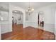 Open-concept dining room with chandelier, wainscoting, hardwood flooring, and seamless flow to other living spaces at 12802 Waterlyn Club Dr, Charlotte, NC 28278