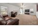Comfortable living room with fireplace, ceiling fan, plush carpeting, and natural light from windows and doors at 12802 Waterlyn Club Dr, Charlotte, NC 28278