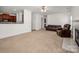 Open-concept living room with fireplace and neutral carpet, flowing into kitchen with wood cabinets at 12802 Waterlyn Club Dr, Charlotte, NC 28278