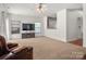 Cozy living room featuring plush carpet, ceiling fan, entertainment center, and comfortable leather seating at 12802 Waterlyn Club Dr, Charlotte, NC 28278