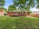 Brick home's backyard with a wooden deck and expansive lawn, perfect for Gathering gatherings and outdoor enjoyment at 1422 Burnley Rd, Charlotte, NC 28210