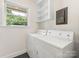 Functional laundry room includes a washer, dryer, shelving, and a bright window at 1422 Burnley Rd, Charlotte, NC 28210