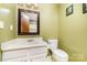 A cozy bathroom features a mirror, toilet, and sink with white cabinets and light green walls at 154 Seven Oaks Ln, Statesville, NC 28677