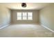 An empty bedroom with wall to wall carpeting and natural light from a large window at 16446 Doves Canyon Ln, Charlotte, NC 28278
