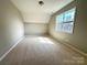 An empty bedroom with wall to wall carpeting and a window allowing natural light at 16446 Doves Canyon Ln, Charlotte, NC 28278