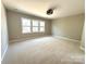 An empty bedroom with wall to wall carpeting and natural light from a large window at 16446 Doves Canyon Ln, Charlotte, NC 28278