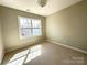An empty bedroom with wall to wall carpeting and a window allowing natural light at 16446 Doves Canyon Ln, Charlotte, NC 28278