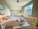 A staged bedroom with two twin beds and a window allowing for natural light at 16446 Doves Canyon Ln, Charlotte, NC 28278