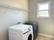 Bright laundry room with Samsung washer and dryer, wire shelving, and natural light from the window at 16446 Doves Canyon Ln, Charlotte, NC 28278