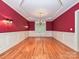 Elegant dining room with red walls, chair rail, chandelier, and hardwood floors at 16511 Bridgehampton Club Dr, Charlotte, NC 28277