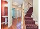 Inviting foyer featuring hardwood floors, a staircase with red carpet and a glimpse of a powder room at 16511 Bridgehampton Club Dr, Charlotte, NC 28277