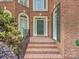Charming entrance featuring a brick walkway, elegant sconces and a classic green front door at 16511 Bridgehampton Club Dr, Charlotte, NC 28277