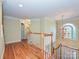 Light-filled landing with hardwood floors, white trim, and a hanging chandelier at 16511 Bridgehampton Club Dr, Charlotte, NC 28277