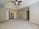 Spacious main bedroom featuring a ceiling fan, tray ceiling, and doors to an ensuite bathroom and walk-in closet at 16511 Bridgehampton Club Dr, Charlotte, NC 28277