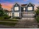 Attractive two-story home features a two-car garage and a well-manicured lawn under a colorful sunset at 17513 Julees Walk Ln, Davidson, NC 28036