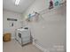 Bright laundry room with white front load washer and dryer, overhead shelving, and tile floors at 17513 Julees Walk Ln, Davidson, NC 28036