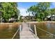 View of a wooden dock leading to a lakeside property with mature trees and clear skies at 17819 John Connor Rd, Cornelius, NC 28031