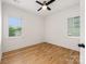 Bright bedroom features hardwood floors, a ceiling fan, and two windows letting in natural light at 2117 Roslyn Ave, Charlotte, NC 28208