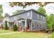 Charming gray two-story home featuring a quaint front porch and well-manicured lawn at 2117 Roslyn Ave, Charlotte, NC 28208