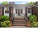 Inviting brick home entrance featuring a glass door, black railings, and decorative shrubbery at 2410 Armstrong Park Dr, Gastonia, NC 28054