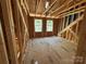 Unfinished room showcasing exposed wooden beams, plywood flooring, and two windows at 28770 Hwy 73 Hwy, Albemarle, NC 28001