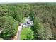Stunning aerial view of the white house with lush green landscaping, pool, and surrounding forest at 317 Marietta Rd, Mooresville, NC 28117
