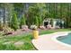 Well manicured lawn and colorful blooms surround the concrete pool area with plenty of shade trees at 317 Marietta Rd, Mooresville, NC 28117