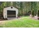 Detached shed with roll up garage door and a manicured lawn surrounded by shade trees at 317 Marietta Rd, Mooresville, NC 28117