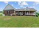 Backyard featuring a brick house with a porch, landscaping, and a well-maintained lawn at 34843 Ellis Spring Ct, Albemarle, NC 28001