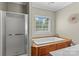 Bathroom featuring a white bathtub, shower with glass door, and window providing natural light at 34843 Ellis Spring Ct, Albemarle, NC 28001