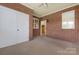 Spacious sunroom with brick accent wall, neutral carpet, and closet access to a view of an open door at 3951 Jasmine Ln, Denver, NC 28037