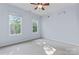 Bright bedroom features a ceiling fan, two large windows with natural light, and neutral-toned carpet at 5022 Saybrook Dr, Harrisburg, NC 28075