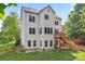 Two-story home features a rear deck, staircase, fenced yard, manicured lawn, and mature shade trees at 5022 Saybrook Dr, Harrisburg, NC 28075