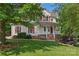 Charming two-story home featuring a covered front porch with classic white columns and well-manicured lawn at 5022 Saybrook Dr, Harrisburg, NC 28075