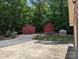 Property featuring outbuildings including two red sheds and a brick structure among mature trees at 5908 Tanson Trl, Marshville, NC 28103